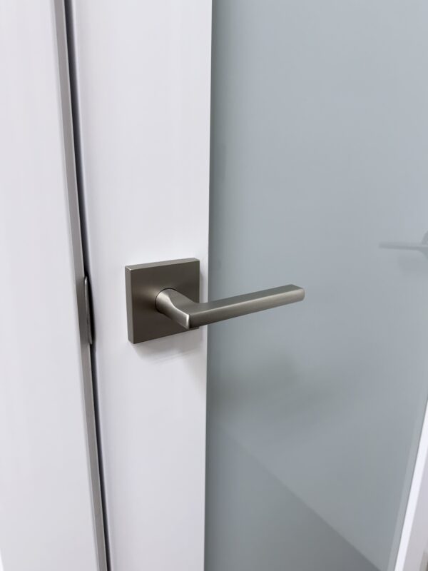 Satin nickel lever handle on a white interior door with frosted glass